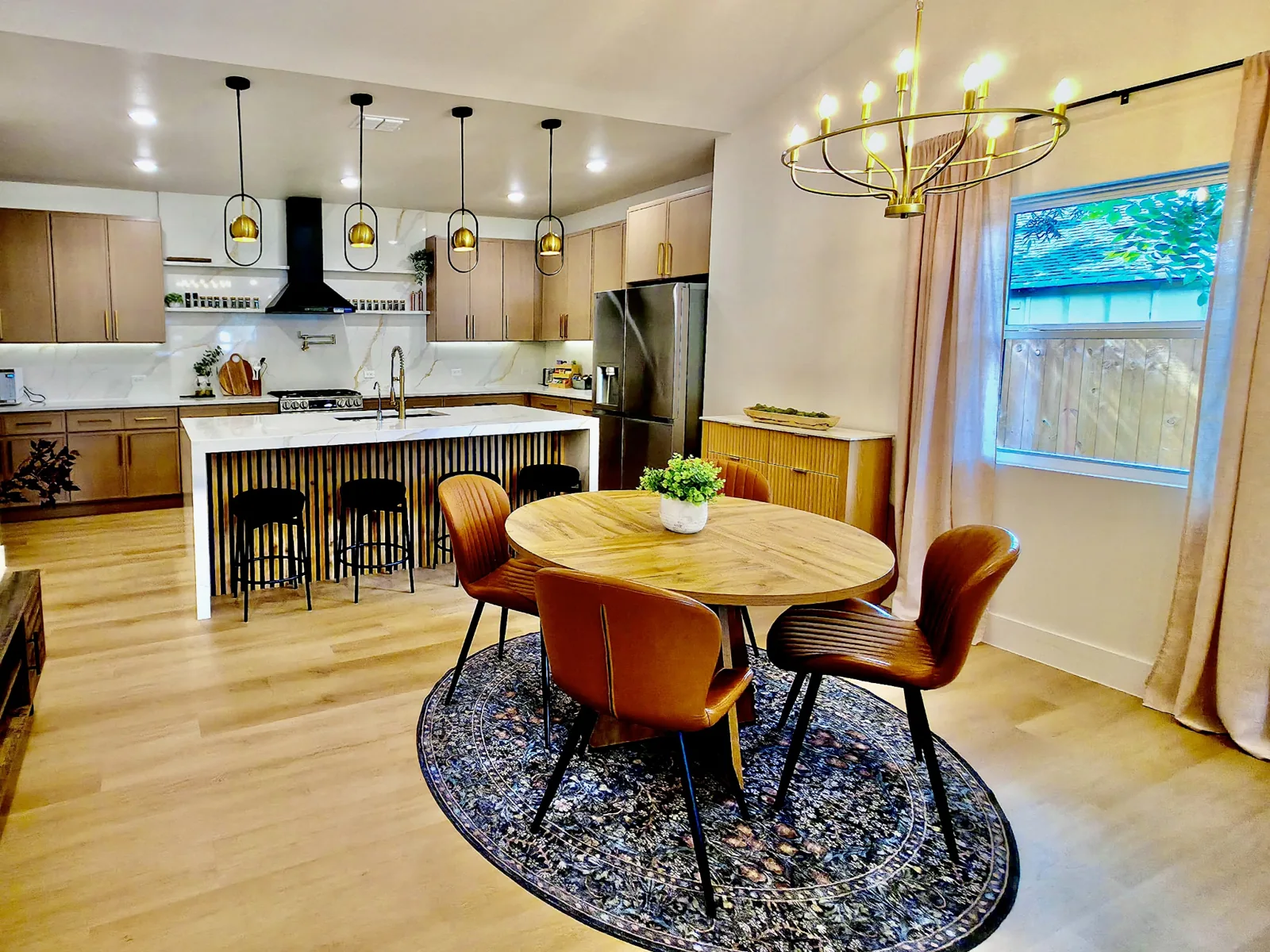 Shared kitchen and dining area with wood cabinetry, gold lighting, and an island